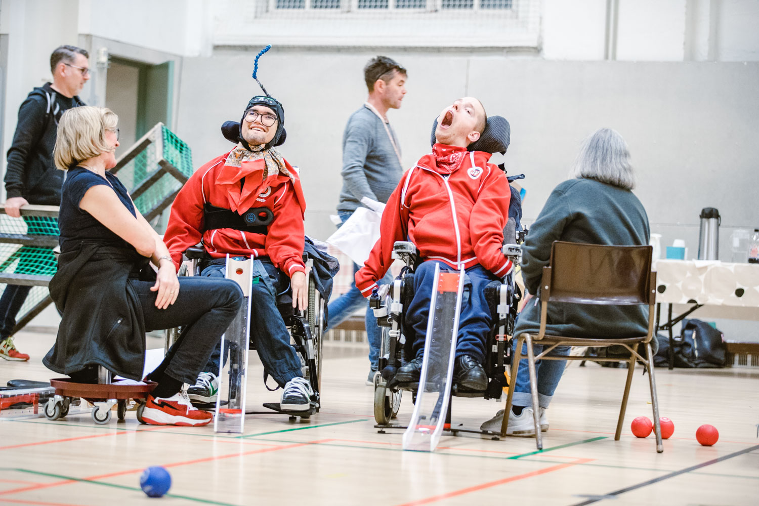 Carl och Einar spelar boccia, assistenterna sitter med ryggen mot kameran.