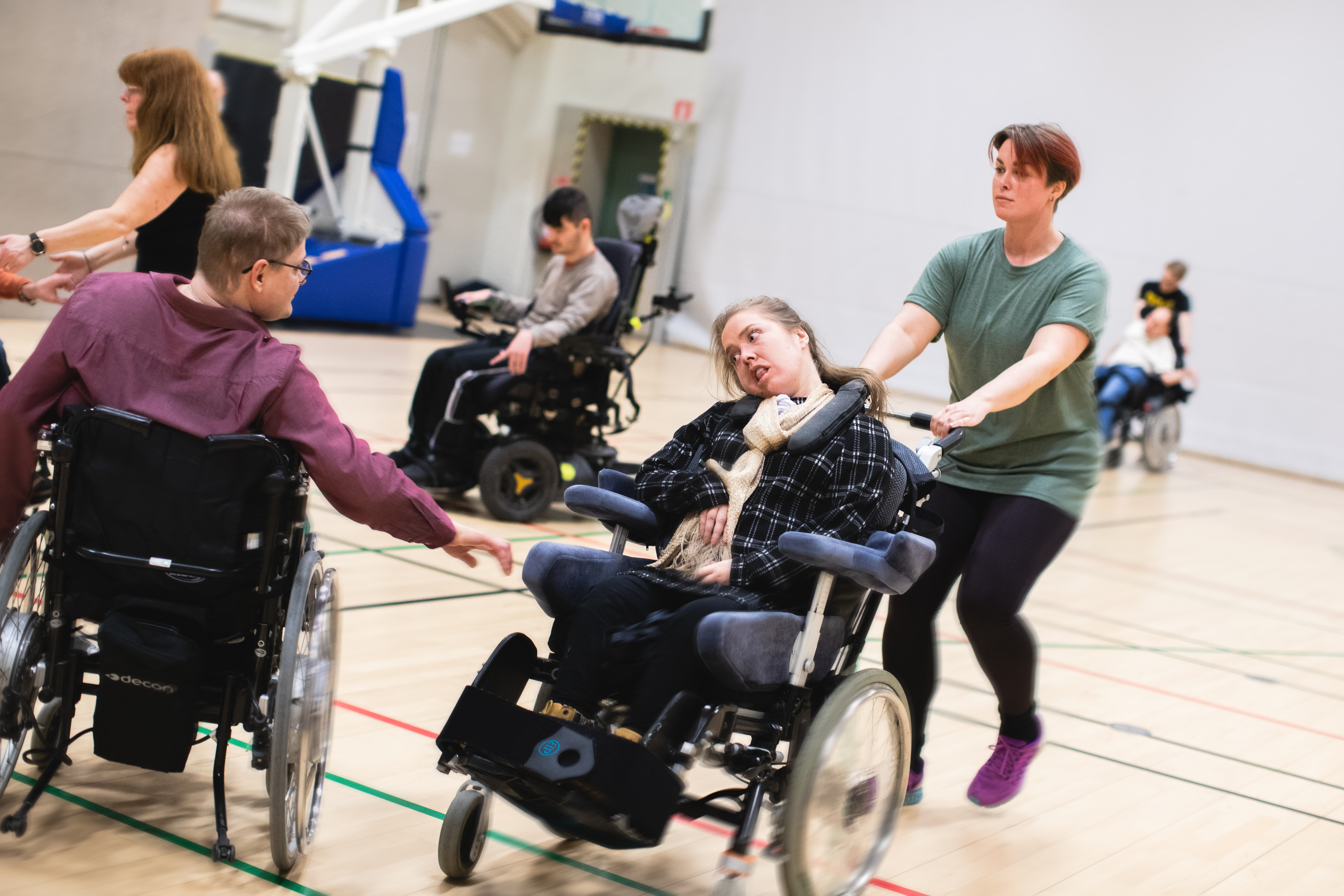 Carl och Einar spelar boccia, assistenterna sitter med ryggen mot kameran.