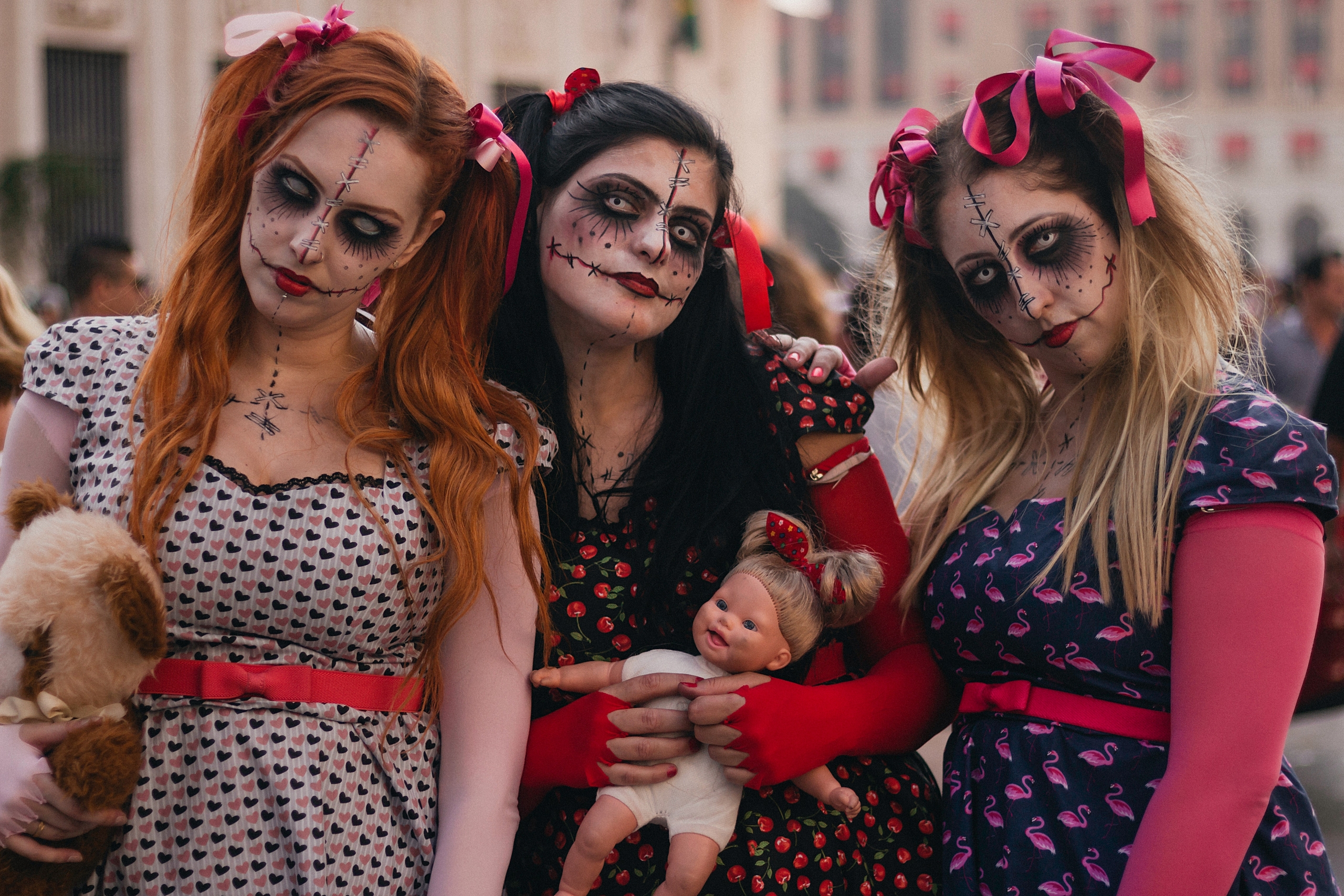 Tre tjejer med halloweensmink och dockor.
