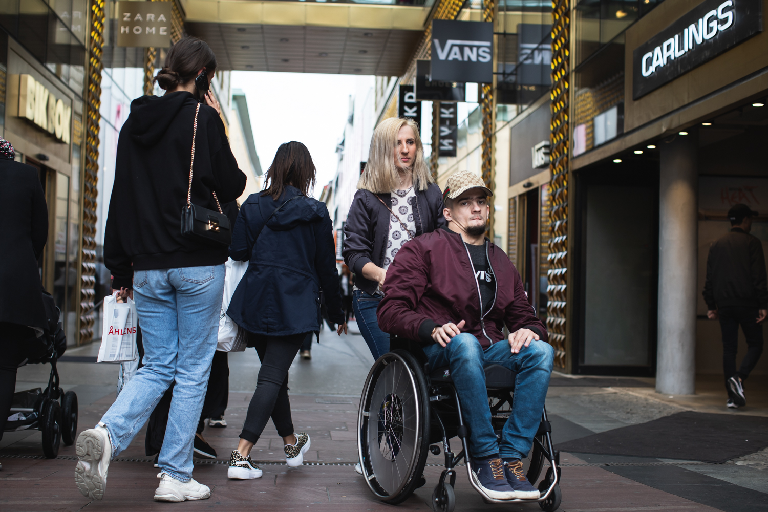 Personlig assistent och person i rullstol, på stan, i Arkaden, Göteborg.