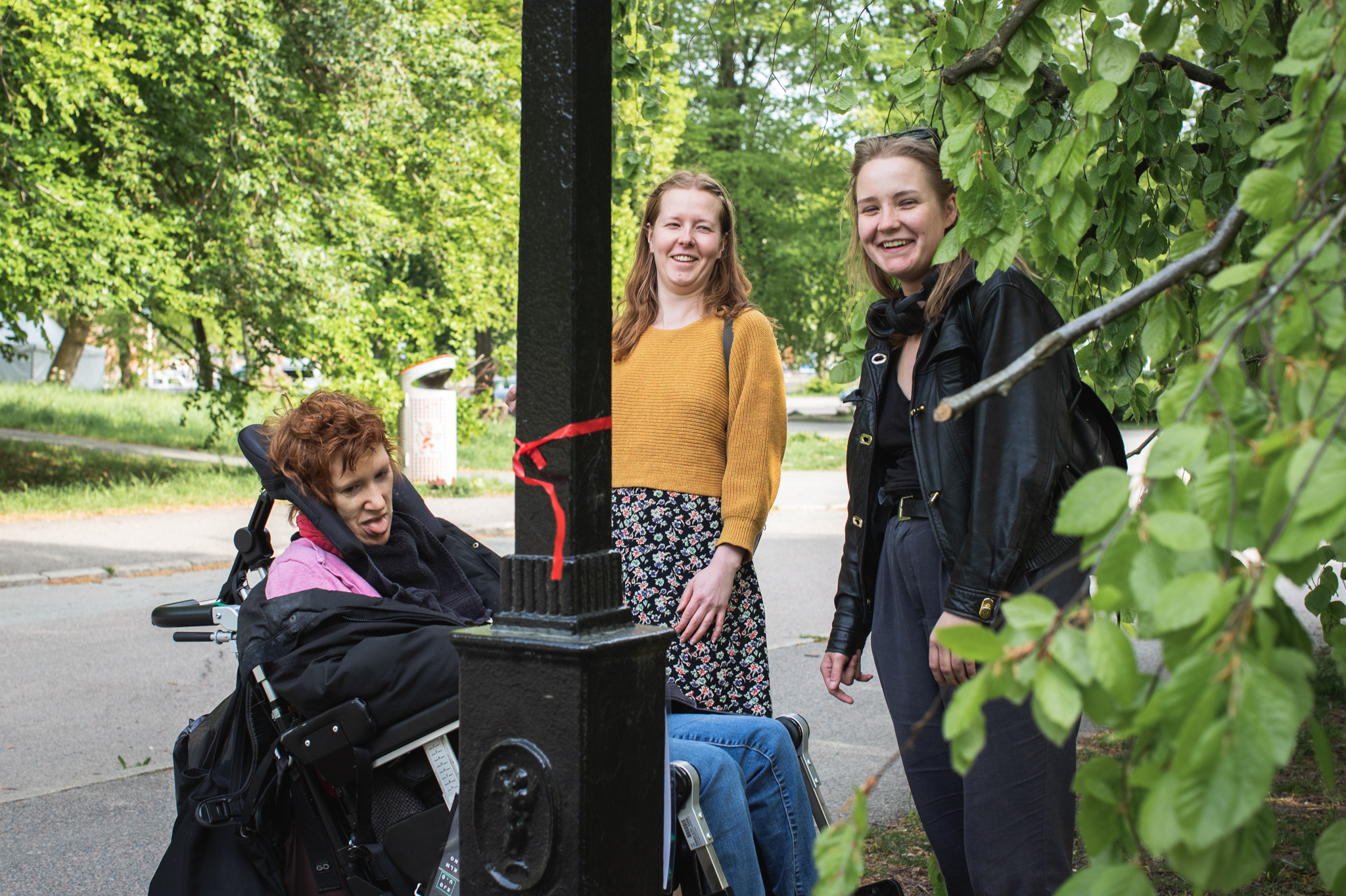 Tre personer i en park, de går tipspromenad. En person använder rullstol.