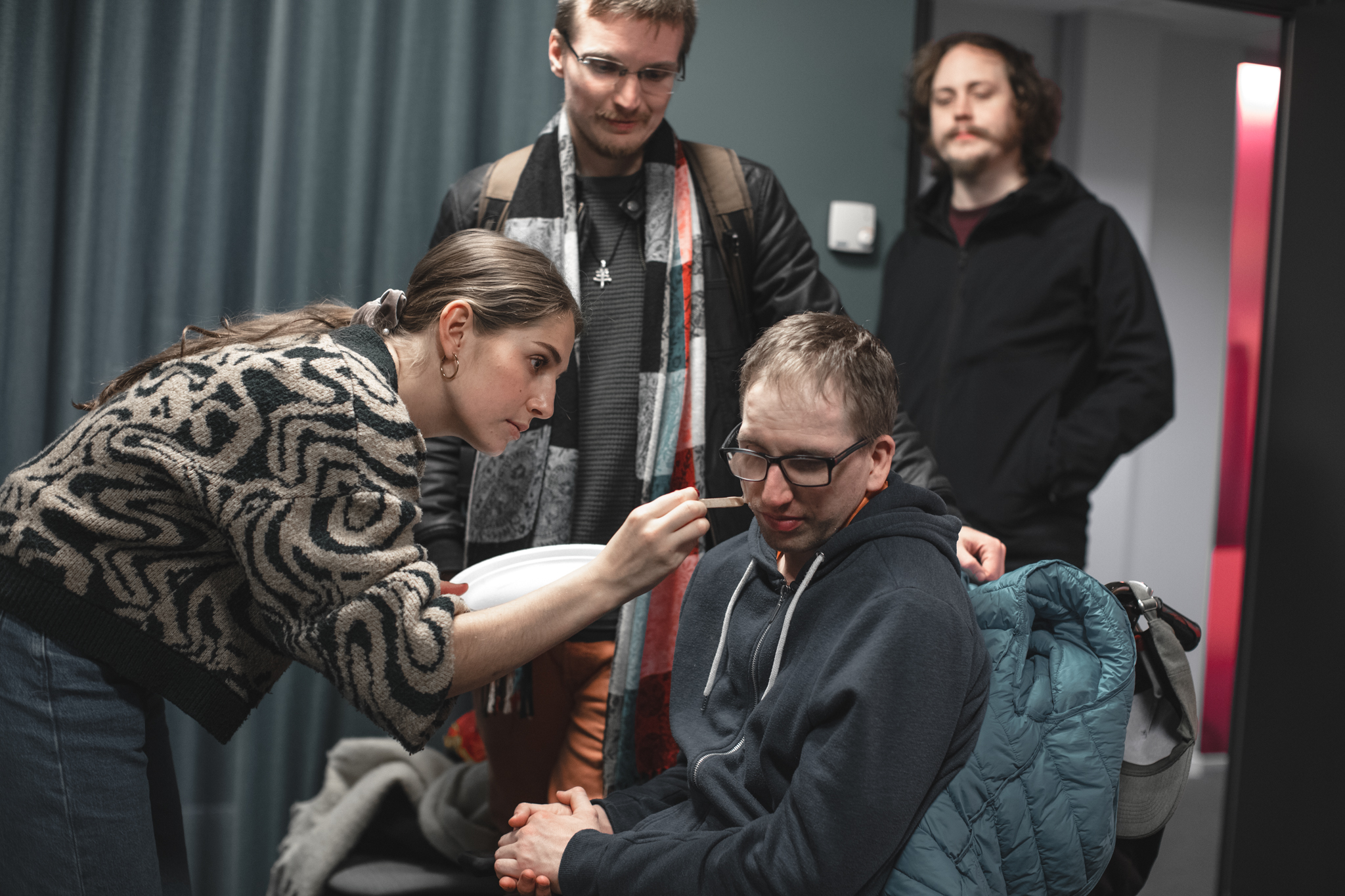 Sminkös skapar ett sår på kille i rullstol, hans två assistenter står i bakgrudnen.