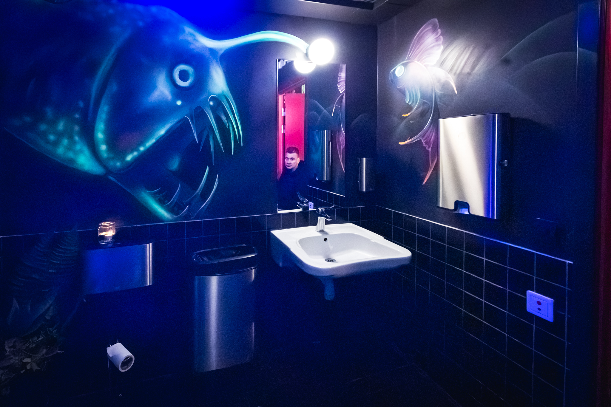 Toaletten på Fiskbar 17 är svart med handmålade fiskar på väggarna, de glöder i UV-ljus