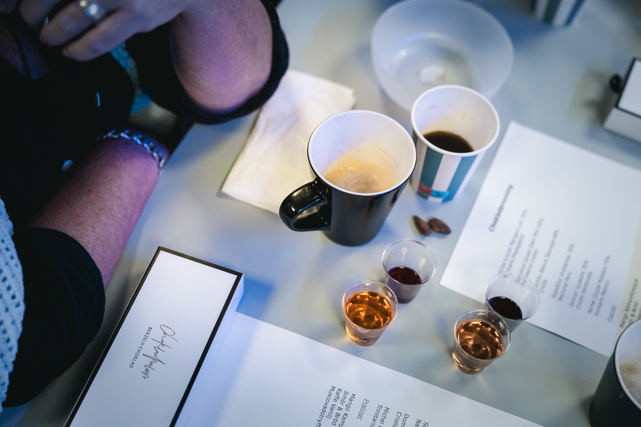 Ovanifrånperspektiv på kaffe, chokladaskar och små provglas med vin.